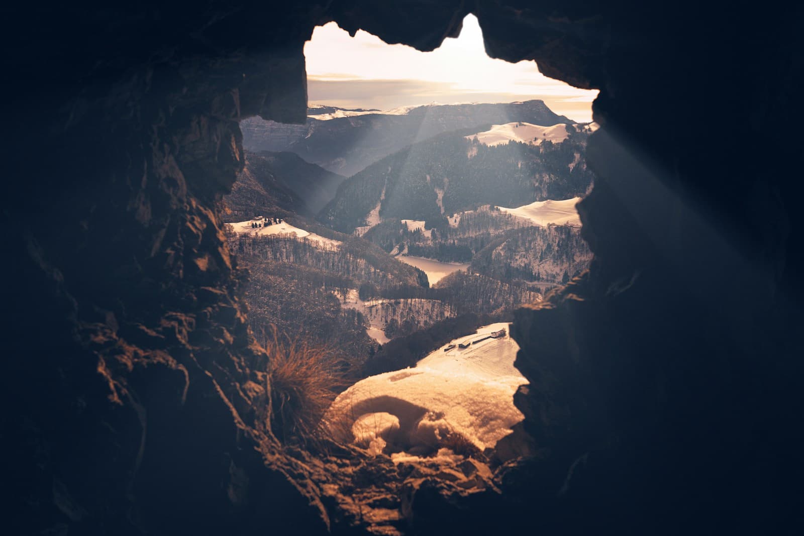 Sunlit mountains seen through the opening of a cave